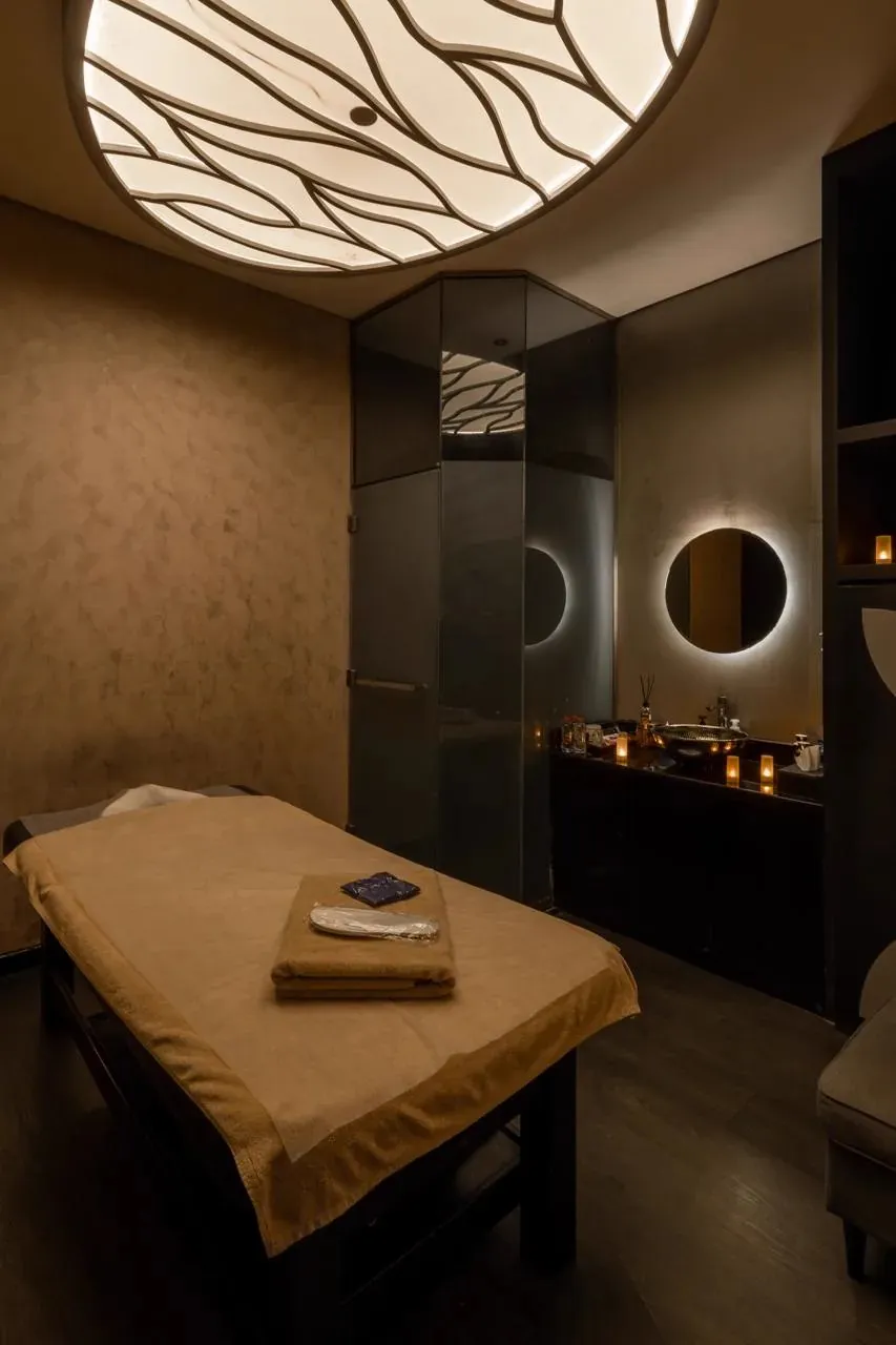 Treatment room with a round backlit mirror and a massage table